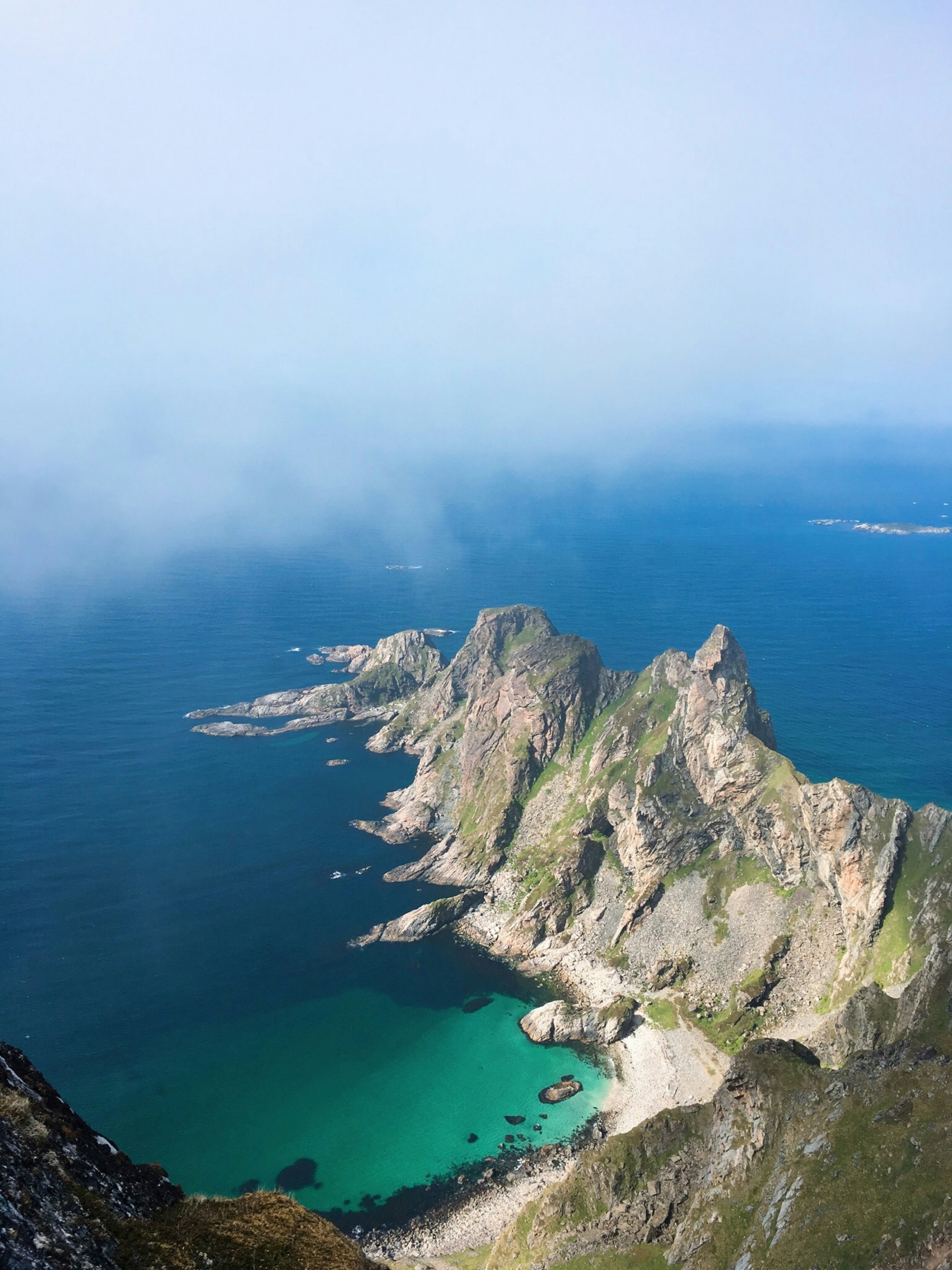 Dramatic sea cliffs extending into the sea in Lofoten, under a clear blue sky